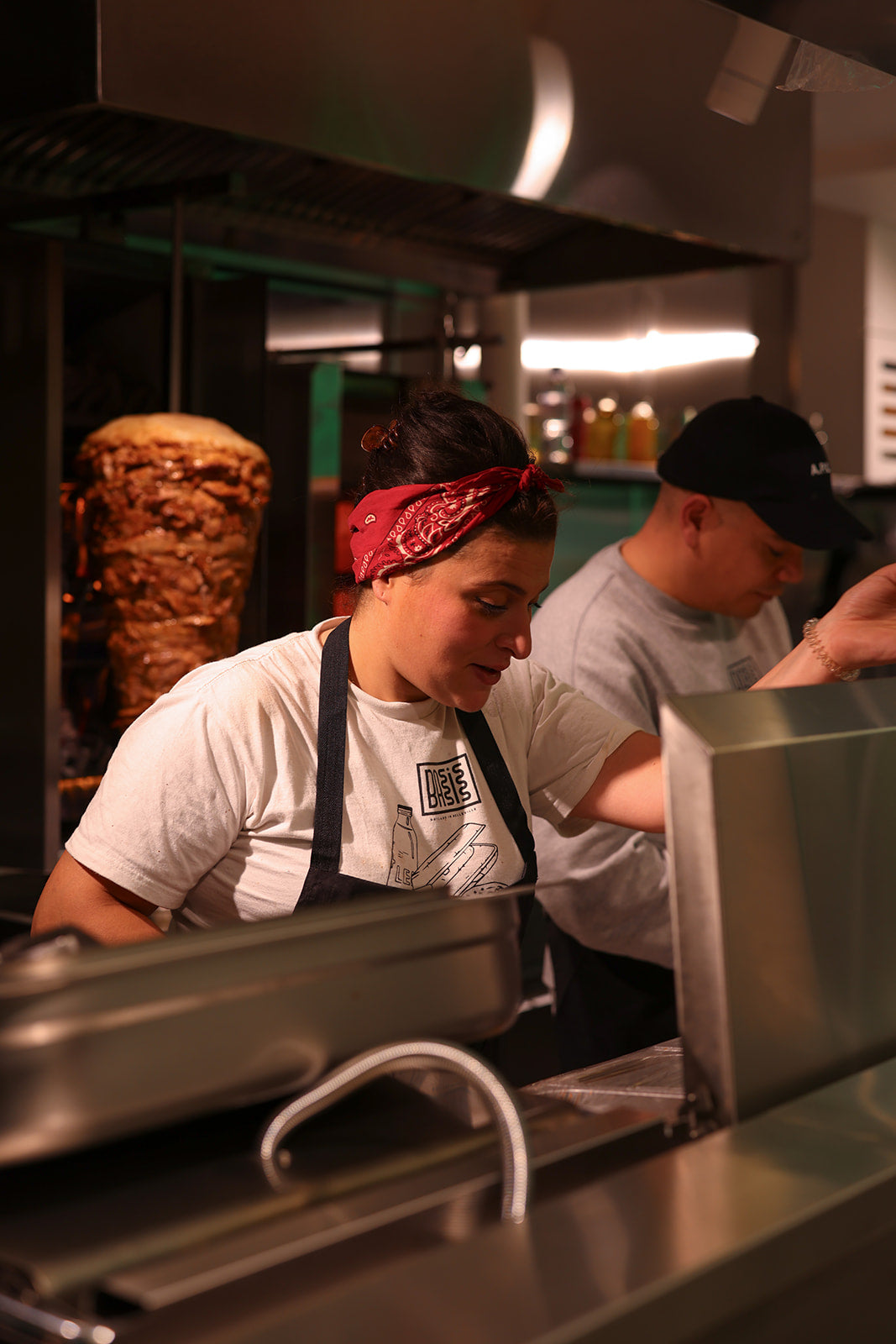 Intérieur Basis Belleville : néon vague vert au plafond, banquettes, cuisine inox