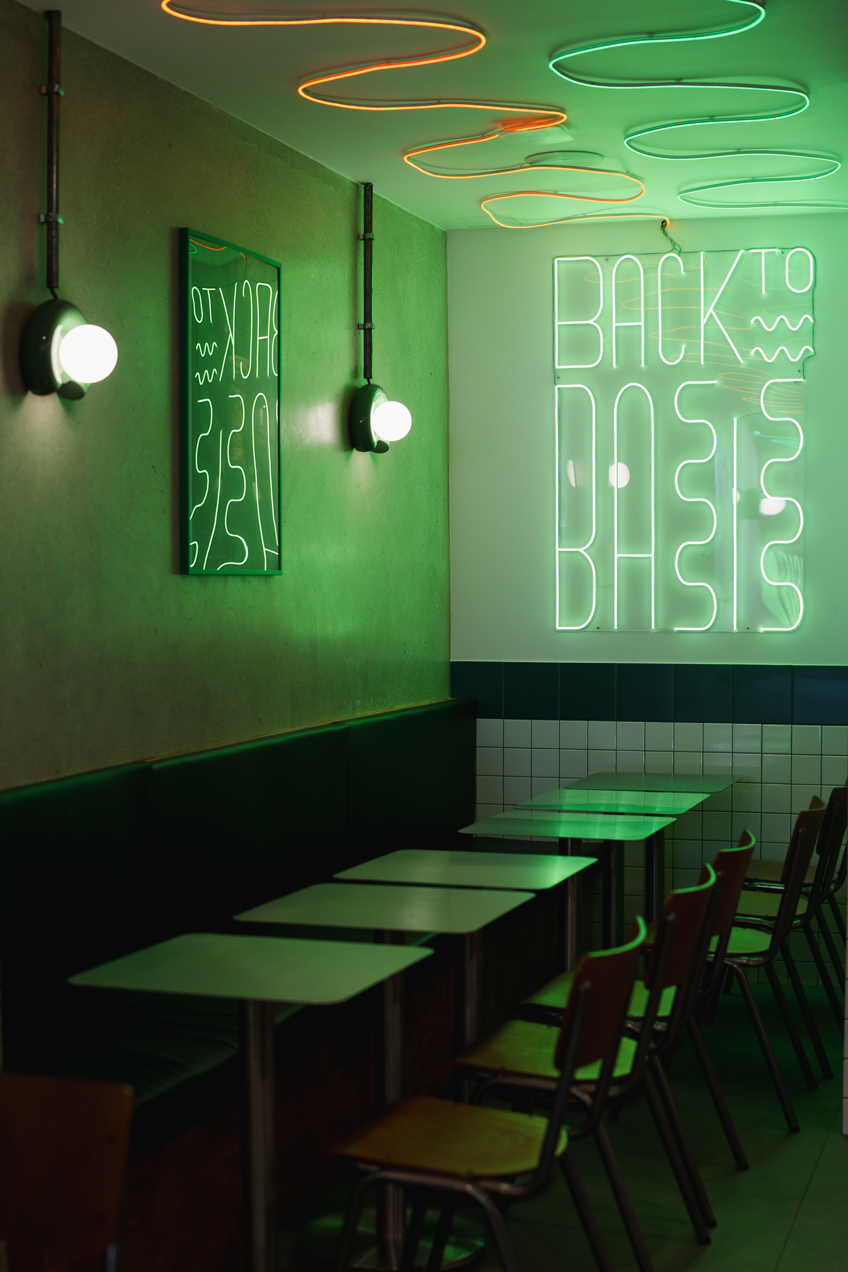 Intérieur Basis Belleville : néon vague vert au plafond, banquettes, cuisine inox
